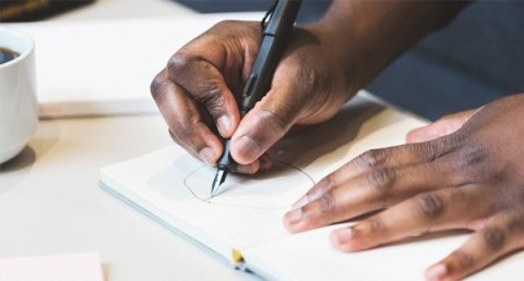 Close-up of man's hands drawing on a piece of paper